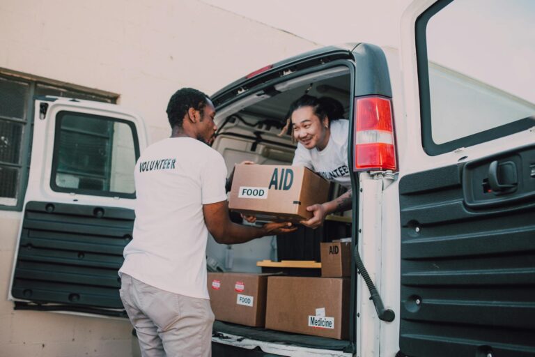 Volunteers unloading boxes of food and medicine from a van for community aid effort.